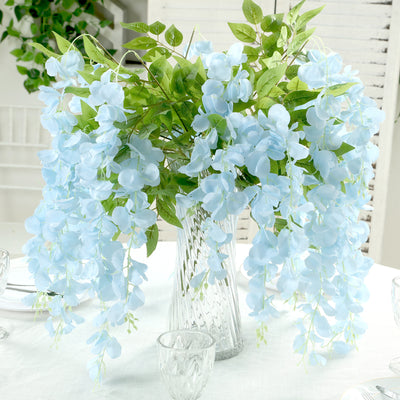 Blue flower arrangement in a clear vase with greenery.