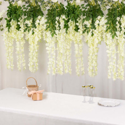 White floral decorations hanging above a table with a basket and gifts.