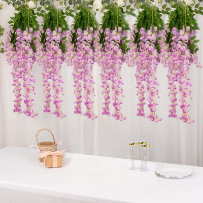 Hanging purple flowers with greenery over a table setting.