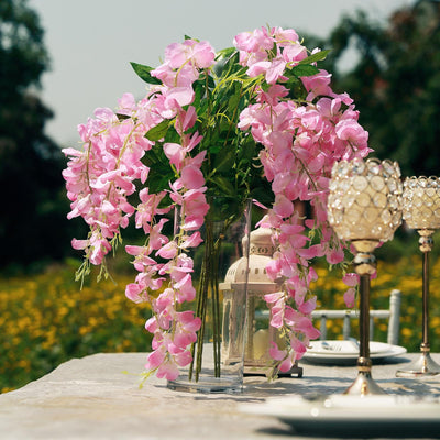 Pink floral arrangement in a vase on a dining table outdoors.