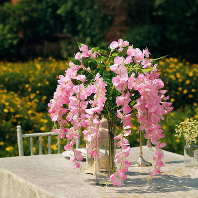 Pink floral arrangement in a glass vase on a table outdoors.