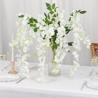 White orchid centerpiece in glass vase for elegant dining decor.