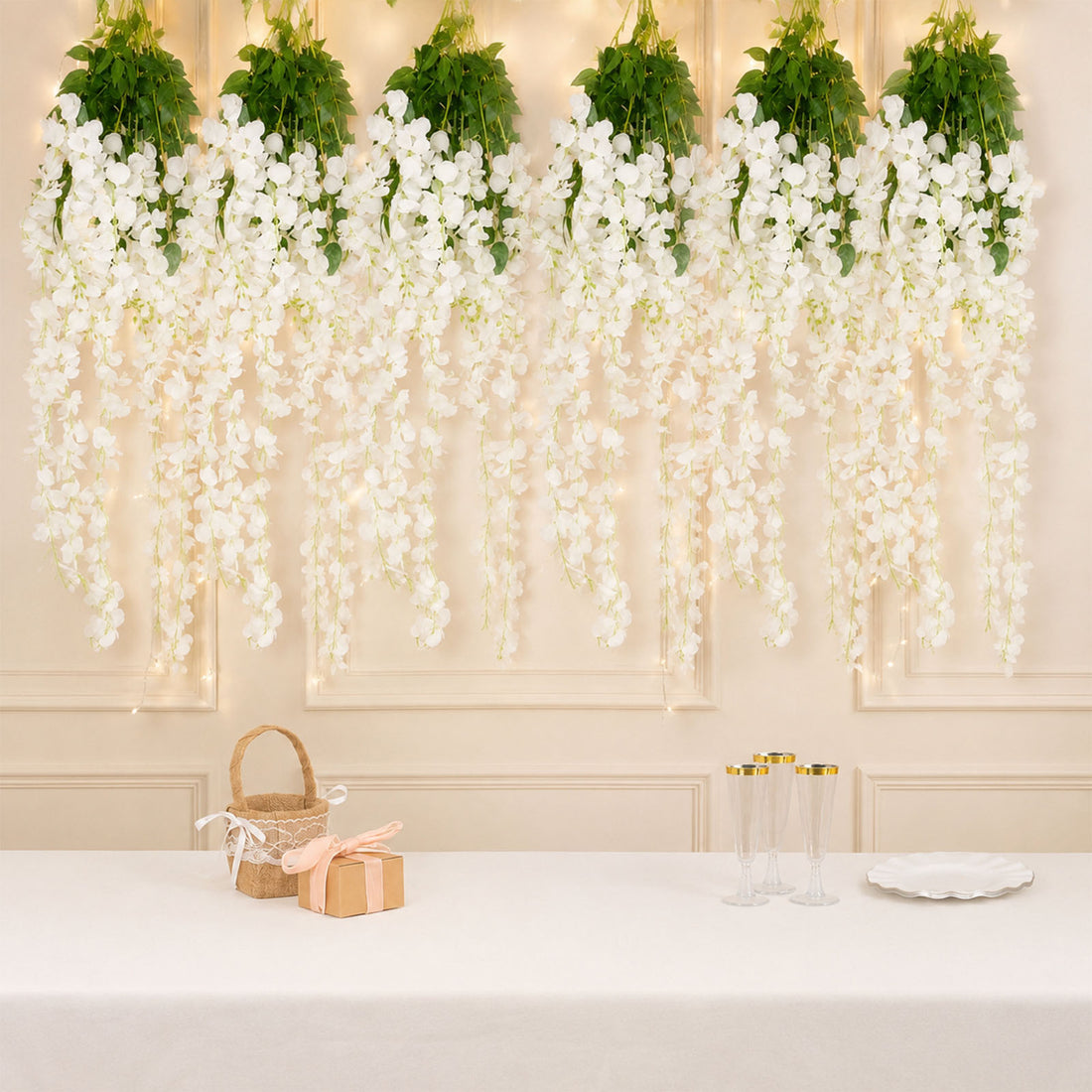 Elegant white floral wall decor with champagne glasses and gift boxes on a table
