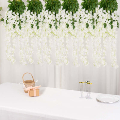 White floral hanging decor above a table with a gift and glassware setup.