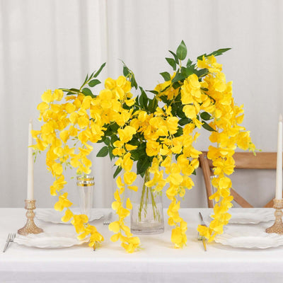 Bright yellow floral arrangement in a clear vase on a dining table.
