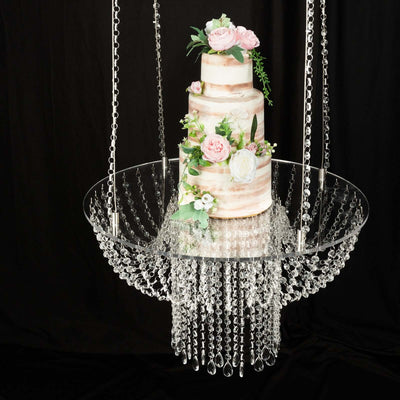 Elegant multi-tier cake adorned with flowers, suspended in a chandelier.