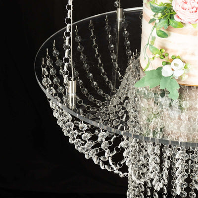 Elegant crystal chandelier with floral cake display on a modern glass table.