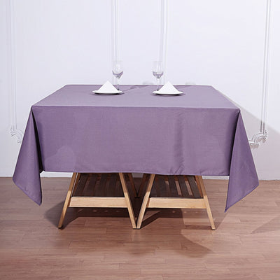 Purple tablecloth draped over a wooden table with plates and glasses