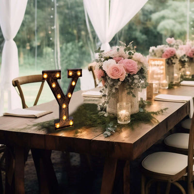 Decorative marquee letter 'Y' with lights at a floral-themed table setting.