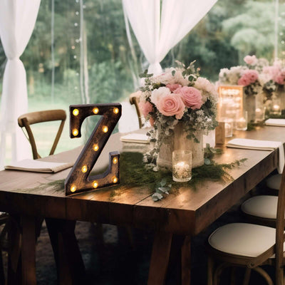 Decorative marquee letter "Z" on a rustic table with flowers and candles.
