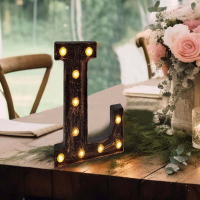 Marquee letter "L" with lights on a rustic table setting.