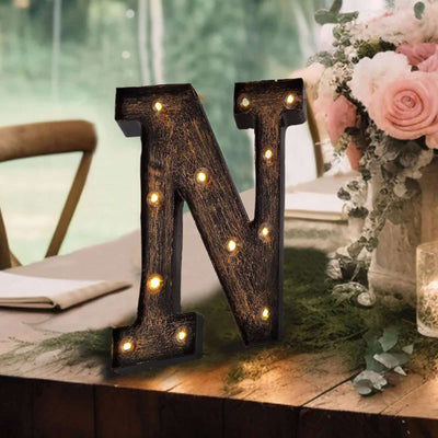 Decorative marquee letter 'N' with lights on a rustic table setting.