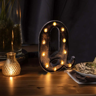 Decorative lit letter "Q" in a cozy setting with warm ambiance.