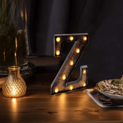 Illuminated wooden letter 'Z' with marquee lights on a rustic table setting.