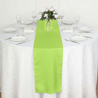 Green table runner on a round dining table set for a meal.