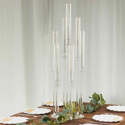 Elegant glass candle holder with multiple tall candles on a wooden table.