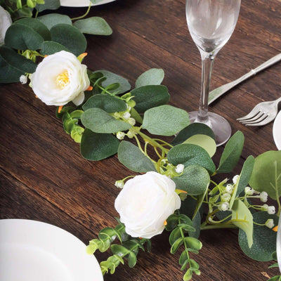 Elegant white floral table centerpiece with greenery on a wooden table.