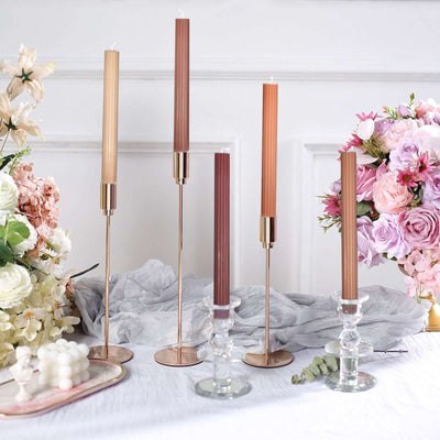Elegant candle holders with colorful candles and floral arrangement in a styled setting.