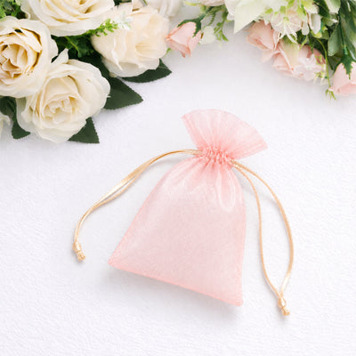 Pink organza drawstring gift bag with white roses on soft white background