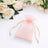 Pink organza drawstring gift bag with white roses on soft white background