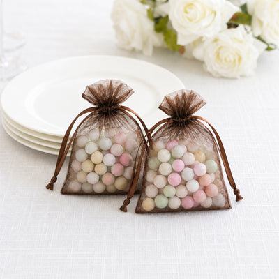 Brown organza gift bags with pastel candy balls on a white table
