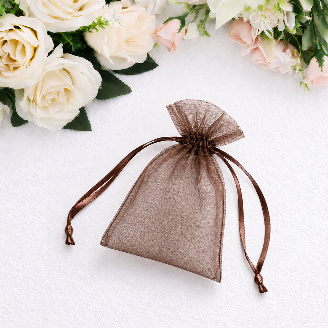 Brown organza drawstring gift pouch on white floral background