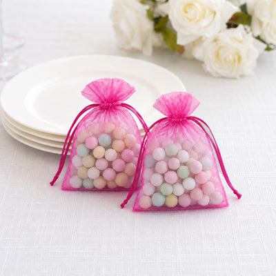Pink organza gift bags with pastel candy beads on a table setting