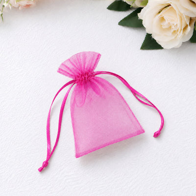 Pink organza drawstring gift pouch on white background with flowers