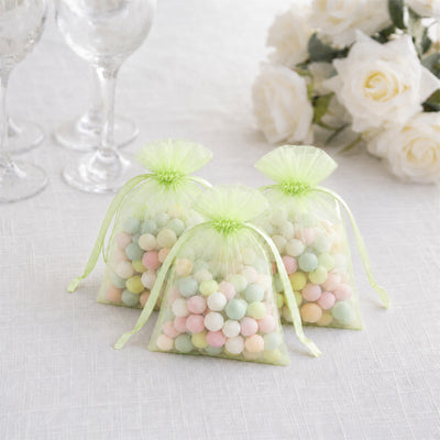 Pastel candy in green organza gift bags with white roses and wine glasses