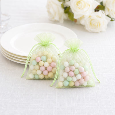 Pastel candy favor bags with colorful sweets and white plates background