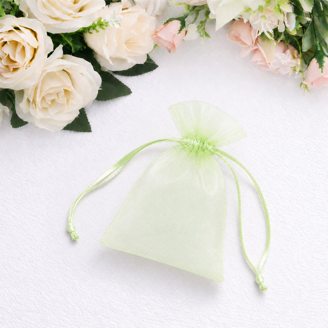 Green organza gift pouch with floral roses on white fabric background