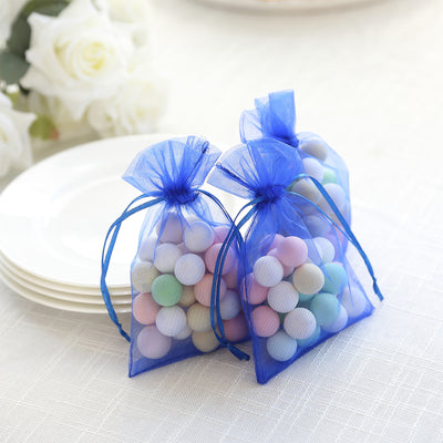 Blue organza bags filled with colorful wooden balls for party favors.