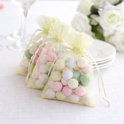 Colorful pastel candy balls in sheer yellow bags for celebrations.