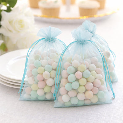 Pastel candy-filled favor bags on a table with plates in the background.