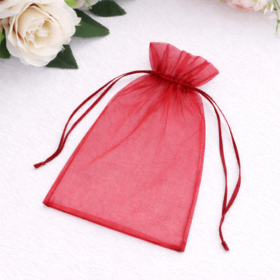 Red organza gift bag with drawstring closure on a soft background.