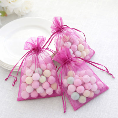 Pink organza bags filled with pastel candy balls on a table.