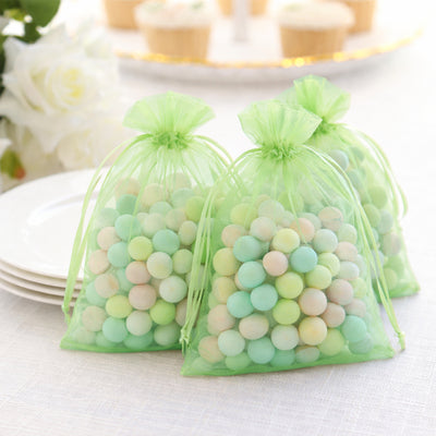 Green mesh bags filled with pastel candy balls for party favors.