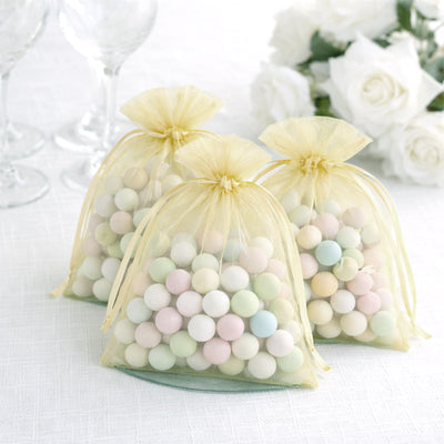 Pastel-colored candy bags with organza ties on a white table.