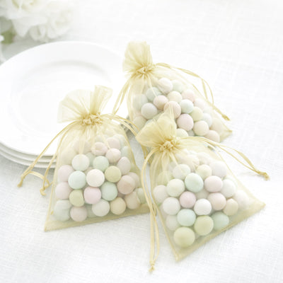 Pastel candy-filled organza bags on a light table setting