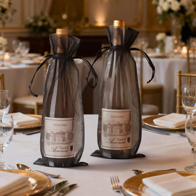 Elegant wine bottles in black organza bags on a beautifully set dining table.