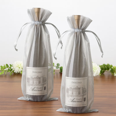 Two elegant wine bottles in decorative gray pouches on a wooden table.