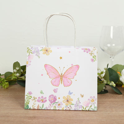 Floral butterfly gift bag with pink and gold accents on a wooden table.