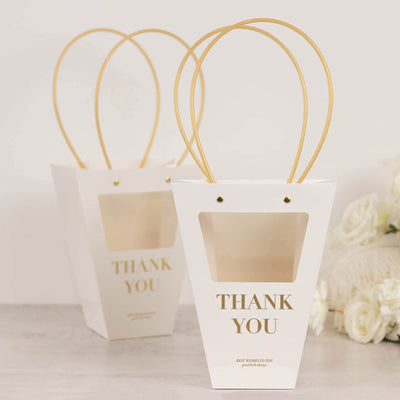White gift bags with gold handles and "Thank You" text