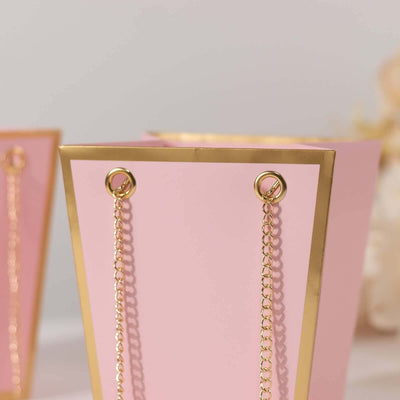 Pink decorative bucket with gold accents and chain handles.