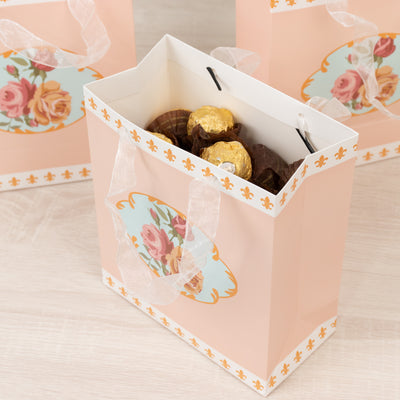 Decorative gift bag with chocolates, featuring floral design and ribbon handles.