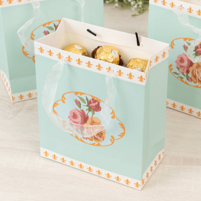 Floral gift bag with chocolate eggs, elegant design and ribbon handles.
