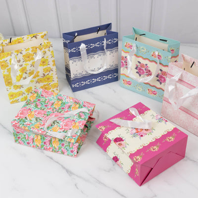Colorful floral gift bags in various designs and sizes on a marble surface.
