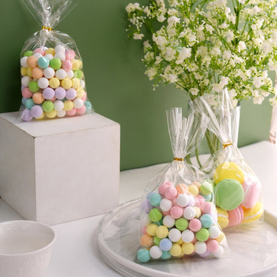 Colorful candy bags on a table with flowers in a vase.