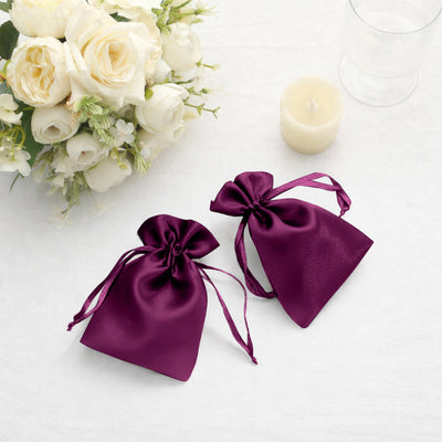 Purple satin gift bags tied with ribbons, styled with flowers and candles.