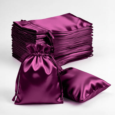 Stack of purple satin bags with a drawstring on a white background